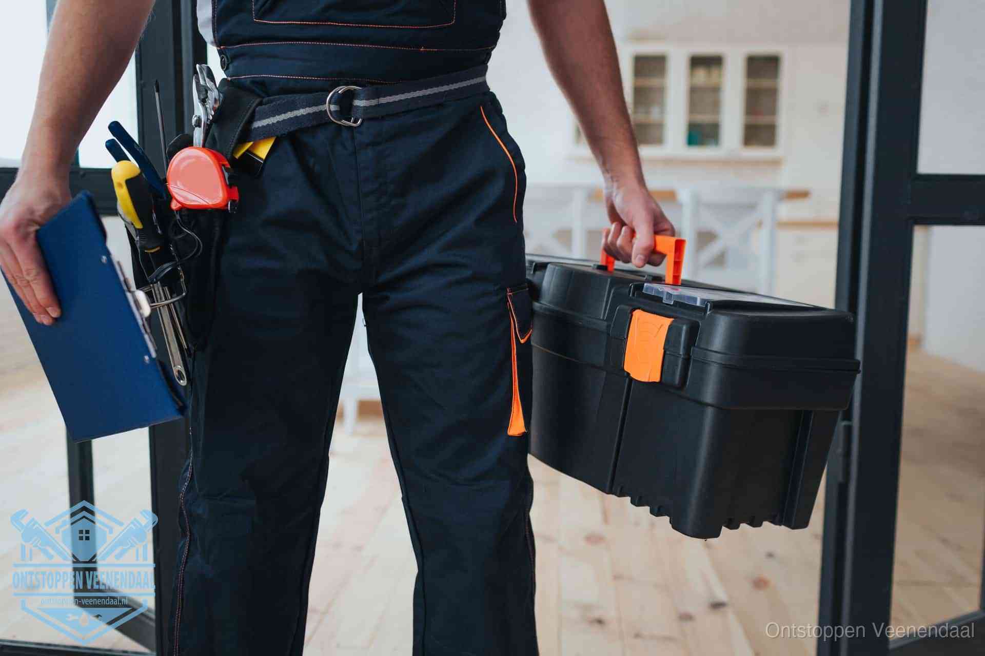 Een monteur met gereedschapsriem en klembord in een keuken, klaar om een transparante prijs voor het gootsteen ontstoppen in Veenendaal te geven