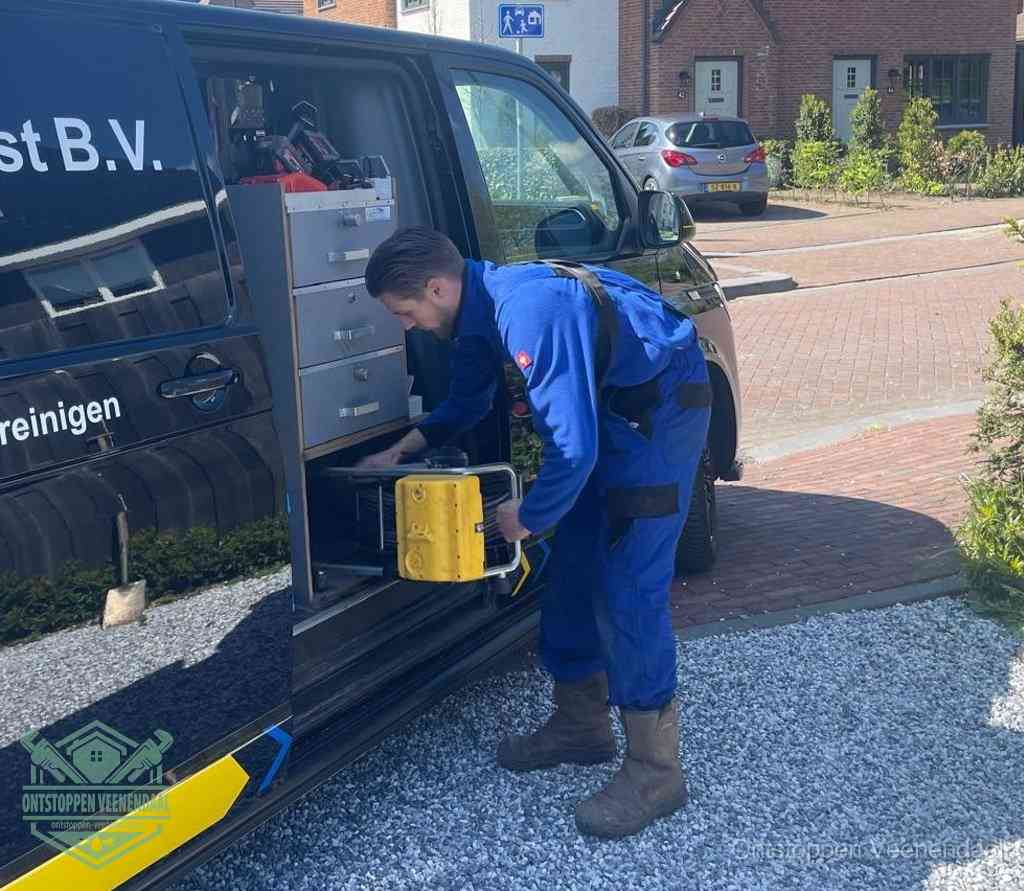 Een monteur pakt buiten op de oprit gereedschap uit de bedrijfsbus, het moment om een professional in te schakelen voor een verstopte afvoer in Veenendaal