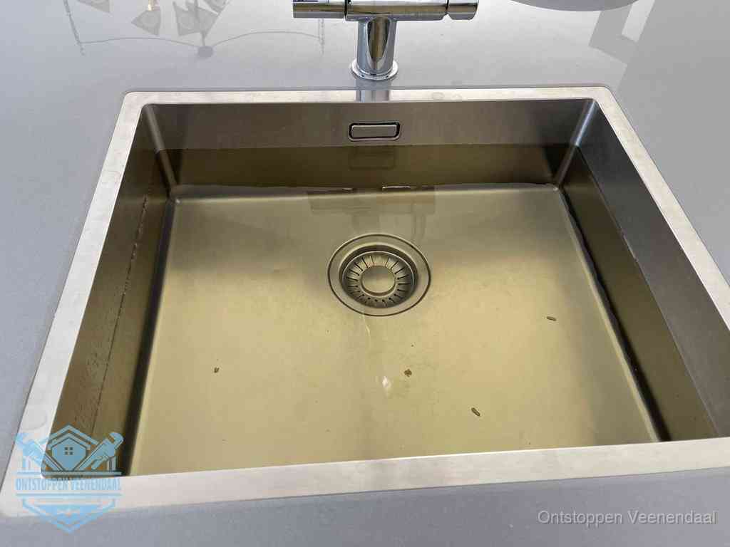 Stilstaand water in een rvs spoelbak dat niet wegloopt, een duidelijk signaal van een gootsteenverstopping in Veenendaal