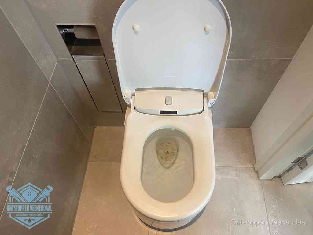 Een wit hangtoilet waarin een prop wc-papier op het water blijft drijven, een duidelijk signaal van een verstopte wc in Veenendaal