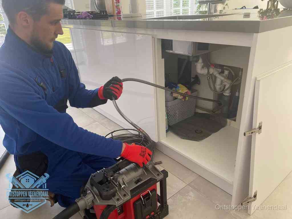 Een monteur reinigt de keukenafvoer grondig met een veermachine om terugkerende gootsteenverstoppingen te voorkomen in Veenendaal