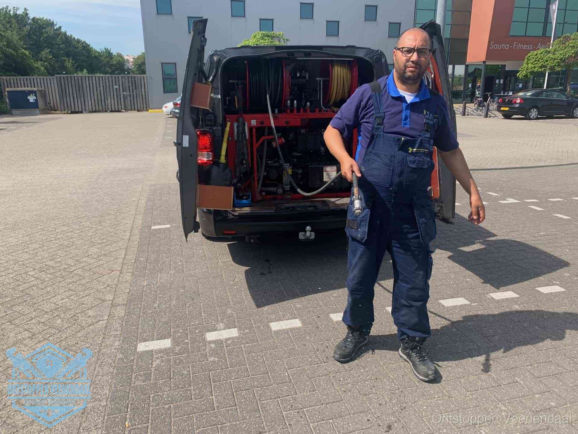 Een monteur bij zijn bestelbus met een hogedruk- en rioolreinigingsunit, klaar om de oorzaak van terugkerende wc-verstoppingen aan te pakken in Veenendaal