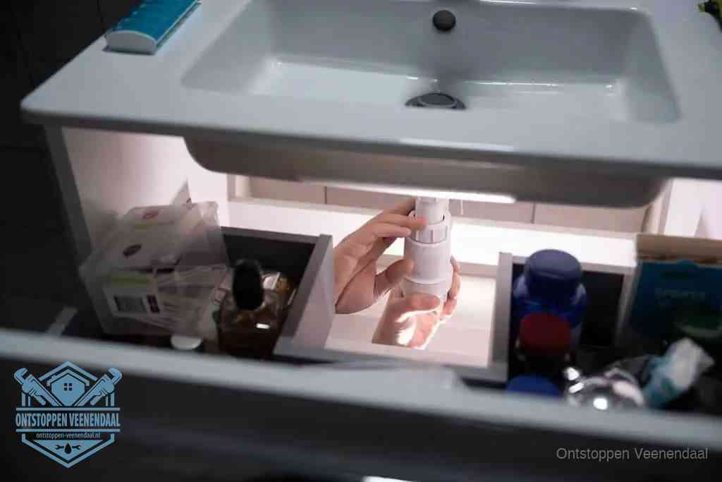 Een pompfles met zeep boven een wastafel in de toiletruimte, de warm water en afwasmiddel-methode om de wc te ontstoppen in Veenendaal