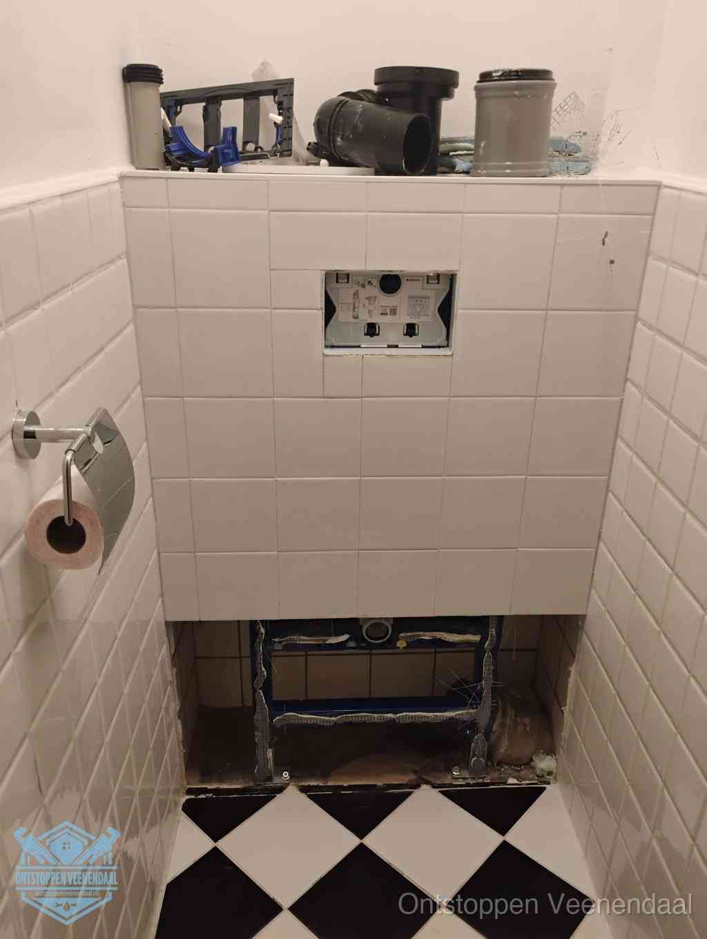 Een toiletruimte waar het hangtoilet en de inbouwreservoir-onderdelen zijn vrijgelegd voor onderhoud, periodiek nazicht voorkomt een wc-verstopping in Veenendaal